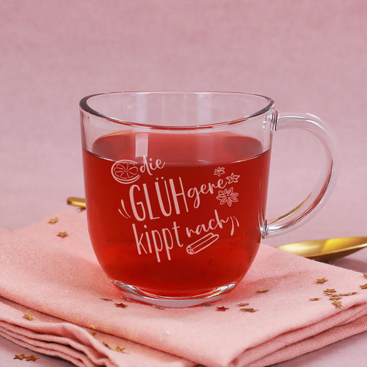 Glühweintasse von Leonardo mit Gravur „Die GLÜHgere kippt nach“, gefüllt mit Glühwein, auf rosa Serviette mit goldfarbenem Löffel