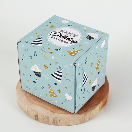 Quadratische Geburtstagsbox auf Holzplatte mit rundum bedrucktem Partymotiv