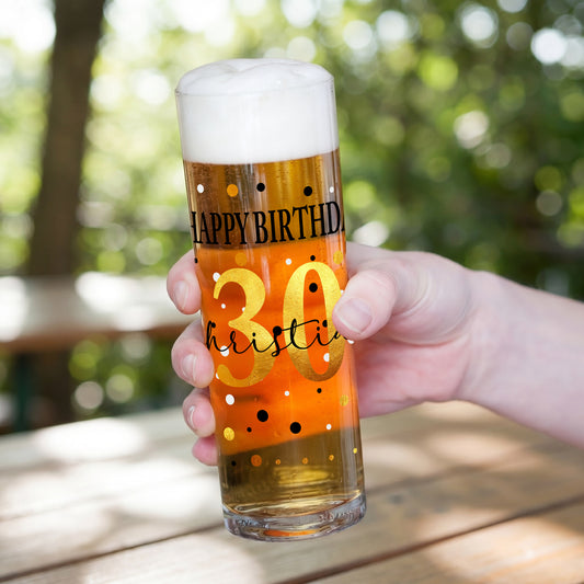 Kölschglas Stange mit Happy-Birthday-Druck, goldener Zahl 30 und personalisiertem Namen, in einer Hand gehalten, gefüllt mit Bier und weißer Schaumkrone.