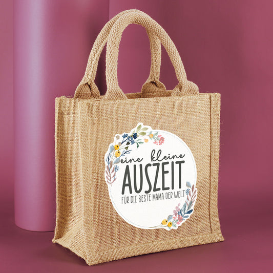 Personalisierte Geschenktasche aus Jute "eine kleine Auszeit" von der Seite fotografiert vor rosa Hintergrund