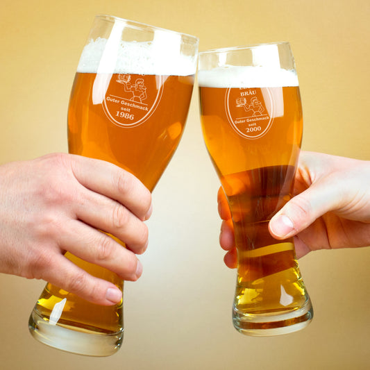 Zwei Hände stoßen mit gravierten Weizengläsern an, Gravur mit Bräu-Logo, Name und Jahr personalisiert