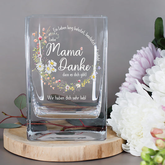 Glasvase mit floralem Druck und Spruch „Ein Leben lang behütet, beschützt und geliebt...“ daneben Chrysanthemen und Eukalyptus
