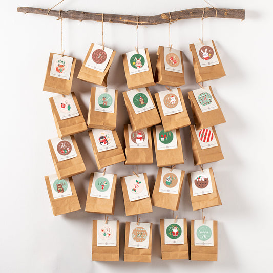 Selbstgemachter Adventskalender an einem Ast aufgehängt, dekoriert mit Tier-Aufklebern und Zahlen von 1 bis 24