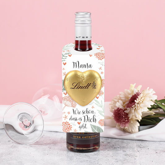 Kleiner Flaschenanhänger (175 x 65 mm) mit Blumendesign und Schokoladenherz an einer schmalen Flasche befestigt.