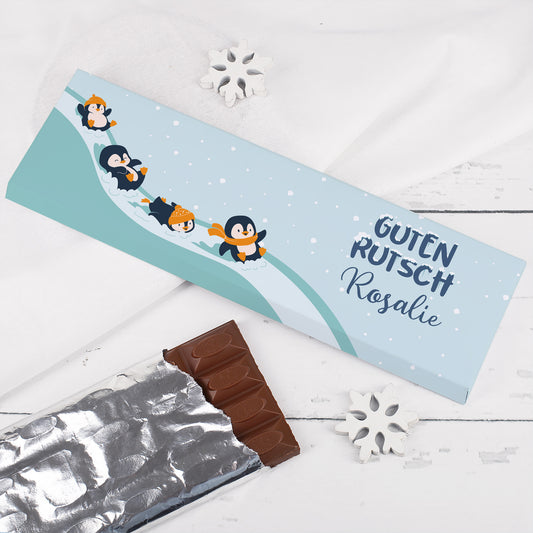 Personalisierte XL-Schokolade mit Pinguinen im Schnee und Aufdruck „Guten Rutsch Rosalie“ – winterliches Geschenk zu Silvester mit ausgepackter Tafel.