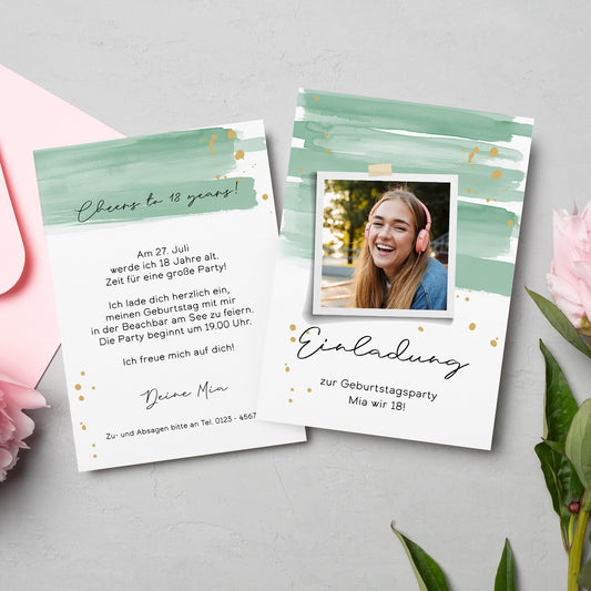 Zwei personalisierte Einladungskarten für eine Geburtstagsfeier, gestaltet mit einem modernen Aquarell-Design in Grün- und Goldtönen. Eine Karte zeigt ein Polaroid-Foto einer jungen Frau mit Kopfhörern, während die andere die Einladungstexte enthält. Umgeben von zarten rosa Blumen und einem Briefumschlag auf hellem Untergrund.