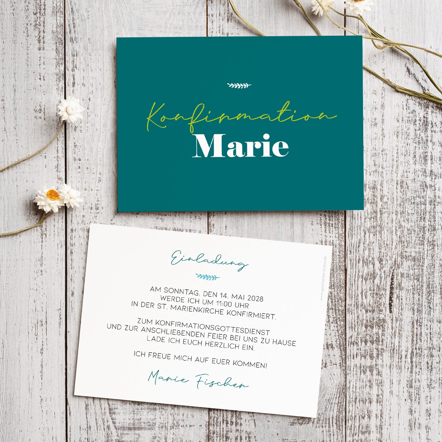 Personalisierte Einladungskarte zur Konfirmation mit modernem Design. Die Vorderseite zeigt den Schriftzug „Konfirmation Marie“ in eleganter Typografie auf petrolgrünem Hintergrund mit einer filigranen Ziergrafik. Die Rückseite ist individuell bedruckt mit einem Einladungstext in stilvoller Schrift. Die Karten liegen dekorativ arrangiert auf einem weißen Holztisch mit kleinen weißen Blüten als natürliche Akzente.
