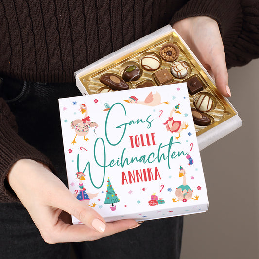 Geöffnete Lindt Pralinenverpackung mit Spruch „Gans tolle Weihnachten Annika“, gehalten in beiden Händen, goldene Einlage mit Schokolade sichtbar.