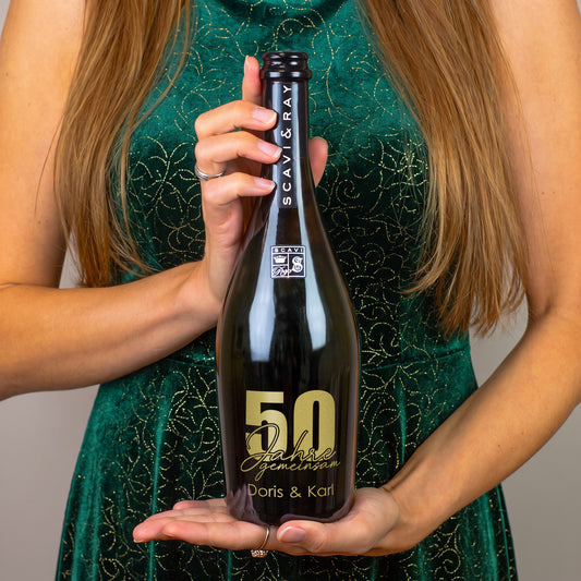 Person hält personalisierte Scavi & Ray Prosecco-Flasche zur goldenen Hochzeit mit Gravur 50 Jahre gemeinsam und Namen Doris & Karl