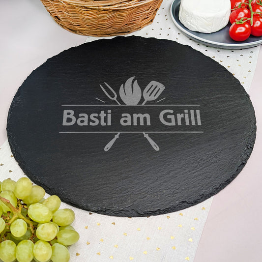 Runde Schieferplatte mit Wunschtext Gravur und Motiv, dekoriert mit Camembert, Tomaten, Korb und Weintrauben.