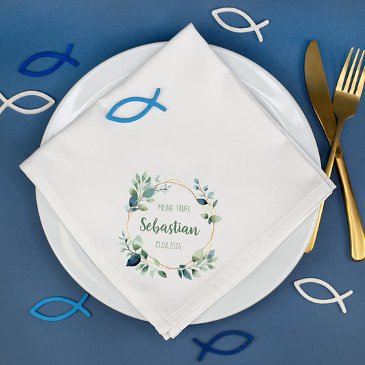 Personalisierte Stoffserviette Taufe mit Eukalyptusmotiv und Name Sebastian auf gedecktem Tisch mit Fischsymbolen