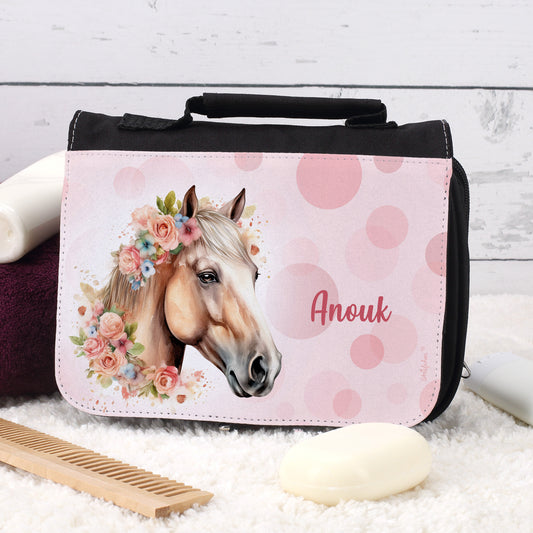 Schwarze Waschtasche mit Blumen-Pferdemotiv und Name „Anouk“ auf Teppich mit Seife und Kamm