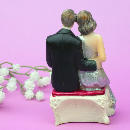 Rückansicht sitzende Hochzeitsfigur – Braut und Bräutigam Arm in Arm auf Bank