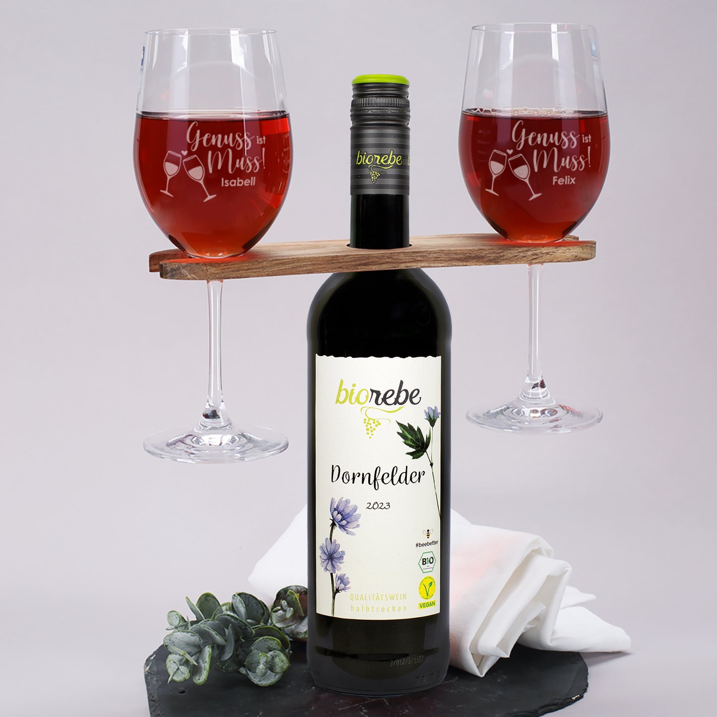 Biorebe Dornfelder mit zwei gravierten Weingläsern „Genuss ist Muss“ auf Holzhalter platziert