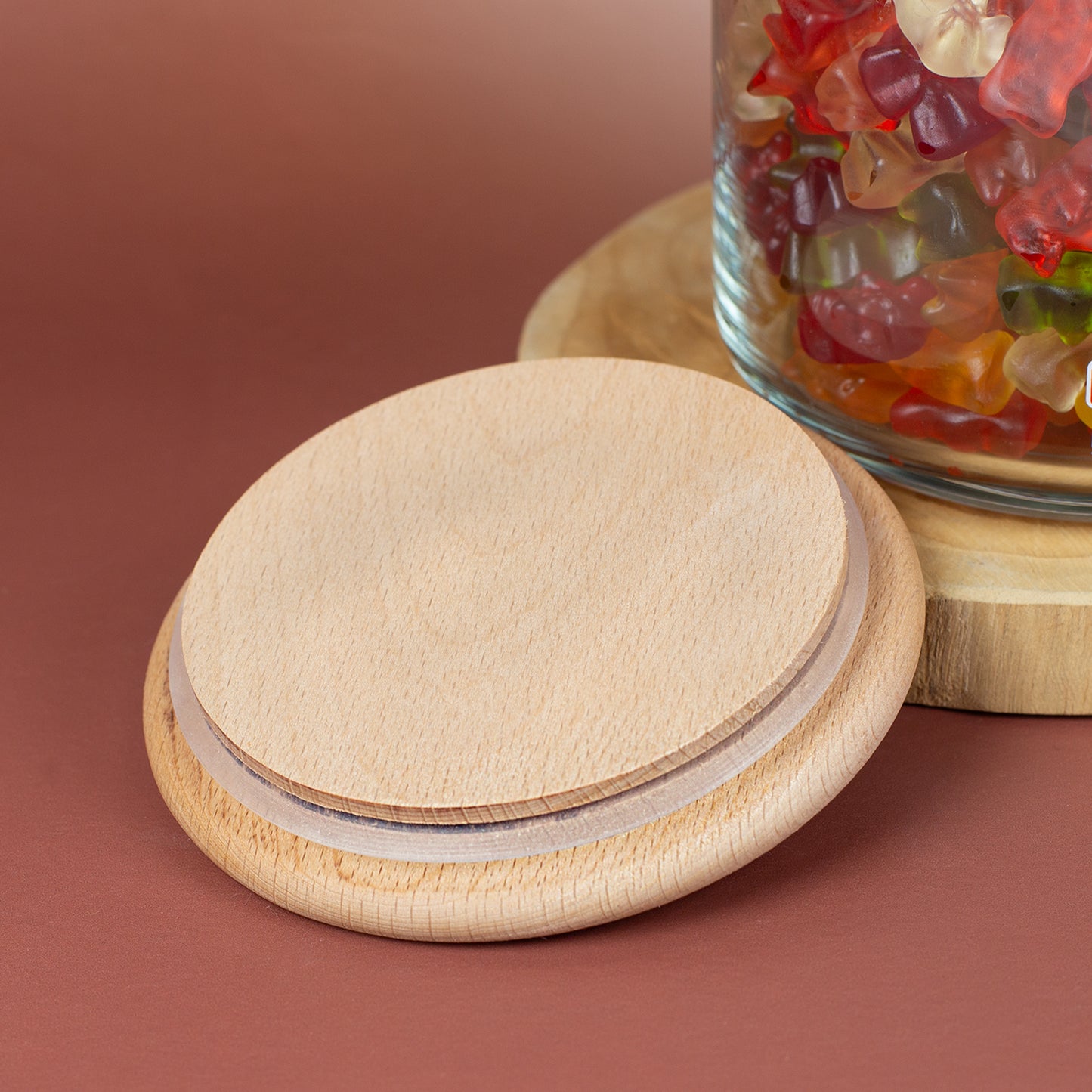 Nahaufnahme vom Holzdeckel mit Silikondichtring neben einem HARIBO Vorratsglas mit bunten Süßigkeiten
