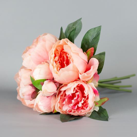 Kunstblumenstrauß mit rosa Pfingstrosen und grünen Blättern – seitlich arrangiert