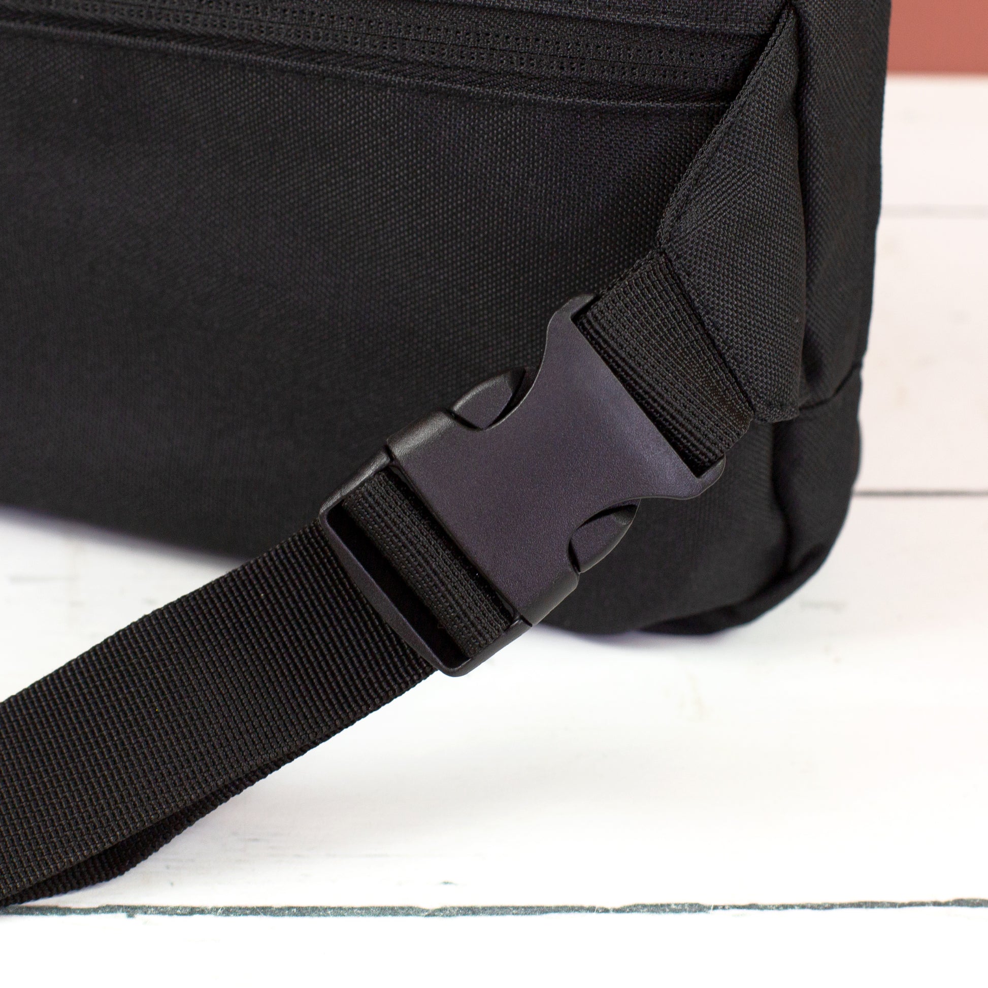 Detailansicht vom schwarzen Clipverschluss und verstellbarem Gurt der Bauchtasche