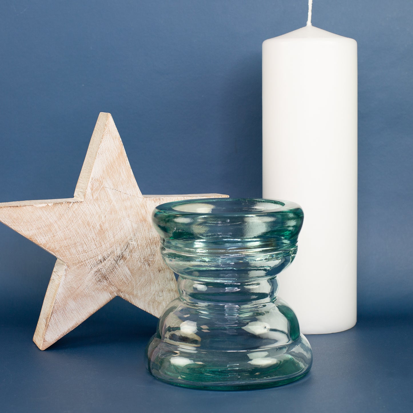 Handgearbeiteter Glas Kerzenhalter mit Holzstern und weißer Kerze vor blauem Hintergrund