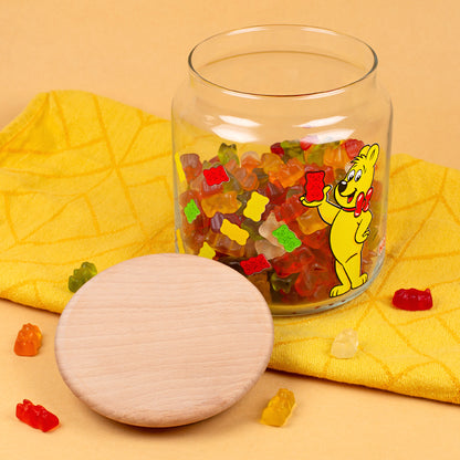 HARIBO Vorratsglas mit Goldbär Motiv, Holzdeckel und bunten Gummibärchen als Dekoration auf gelbem Hintergrund