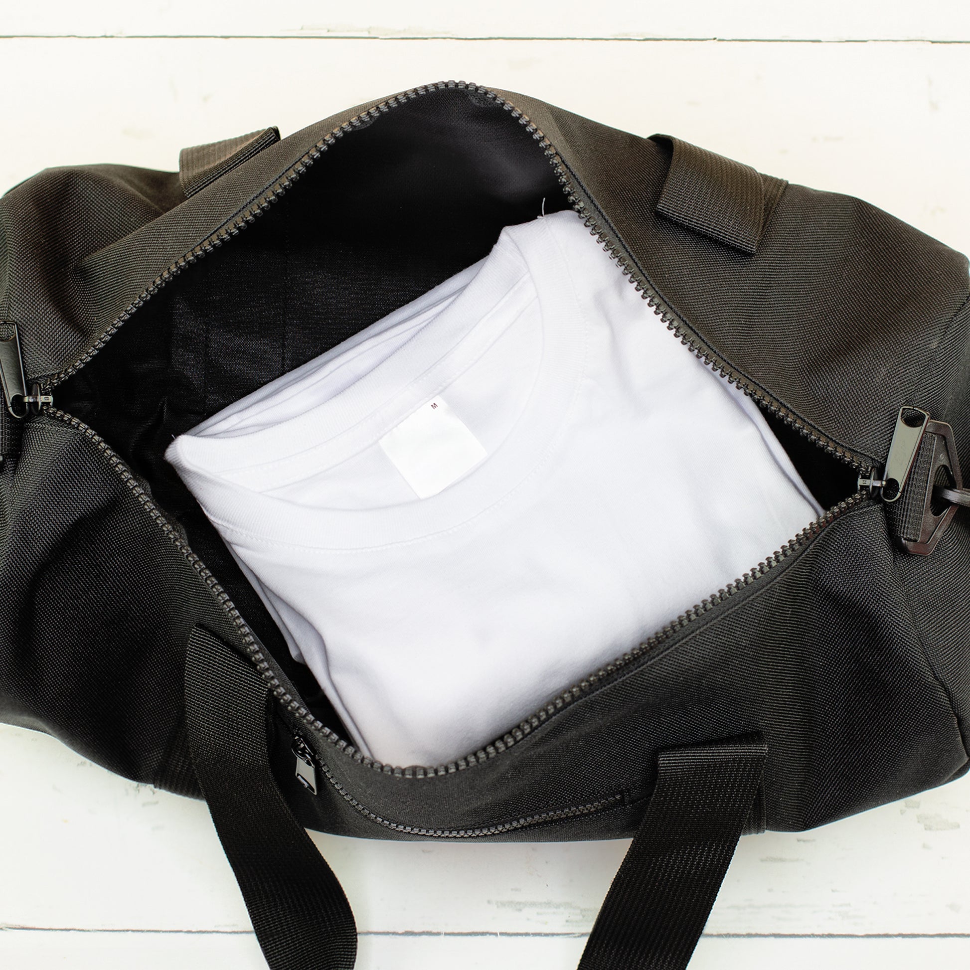 Schwarze Reisetasche mit Kleidung im Hauptfach als kleine Tasche für unterwegs
