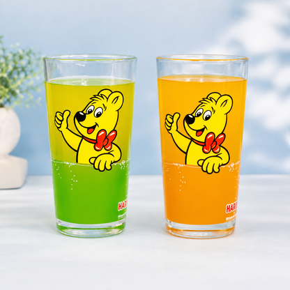 HARIBO Trinkglas Variantenbild mit zwei Gläsern in Grün und Orange, Goldbär Motiv und schlichtem Studiohintergrund