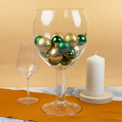 Riesengroßes Weinglas als Tischdeko mit gold-grünen Weihnachtskugeln gefüllt