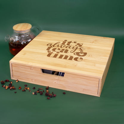 Teebox aus Bambus mit Schublade und It's always tea time Motiv neben einer Teekanne