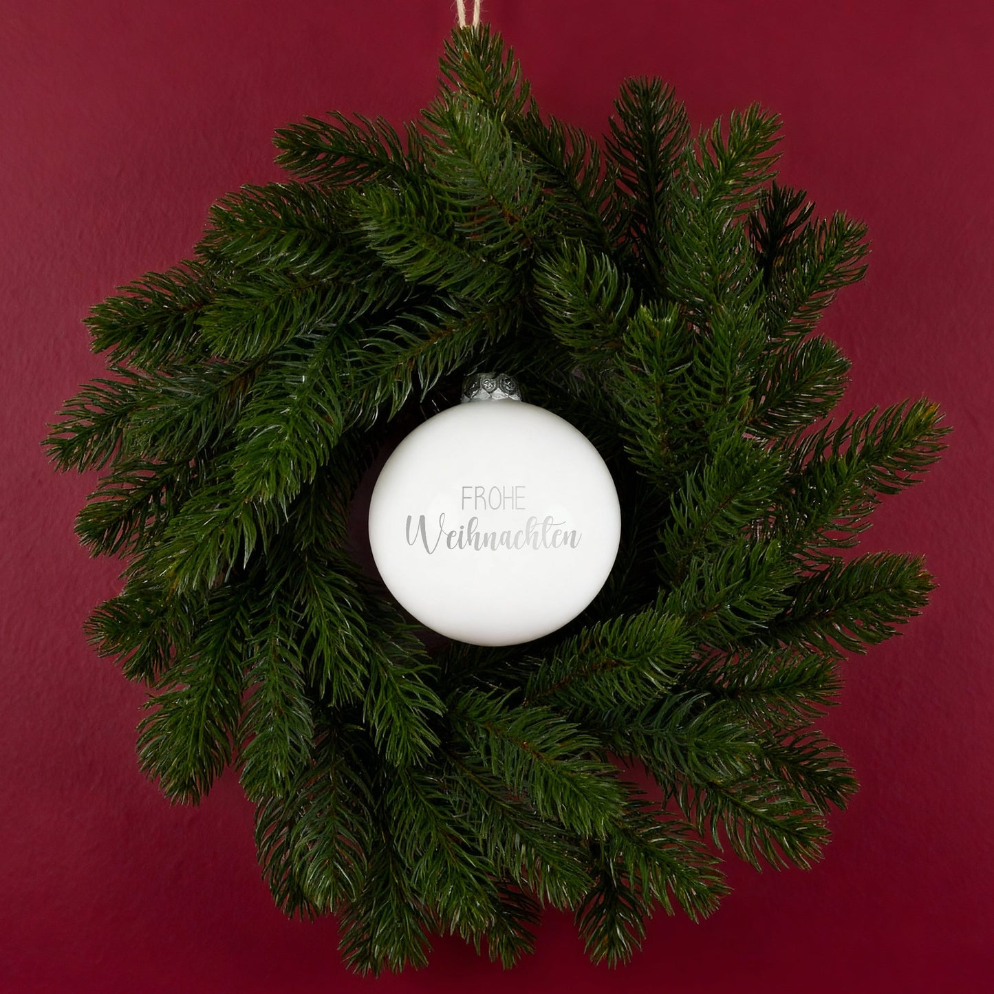 Weihnachtskranz mit weißer Kugel Frohe Weihnachten an roter Wand dekoriert