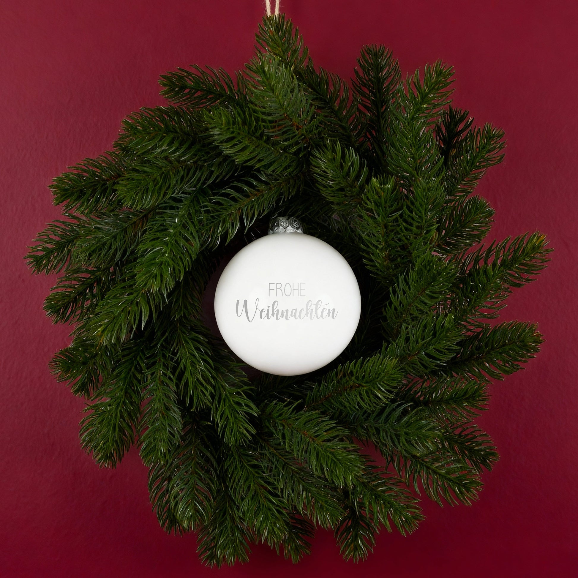 Weihnachtskranz mit weißer Kugel Frohe Weihnachten an roter Wand dekoriert