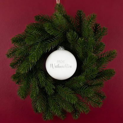 Weihnachtskranz mit weißer Kugel Frohe Weihnachten an roter Wand dekoriert