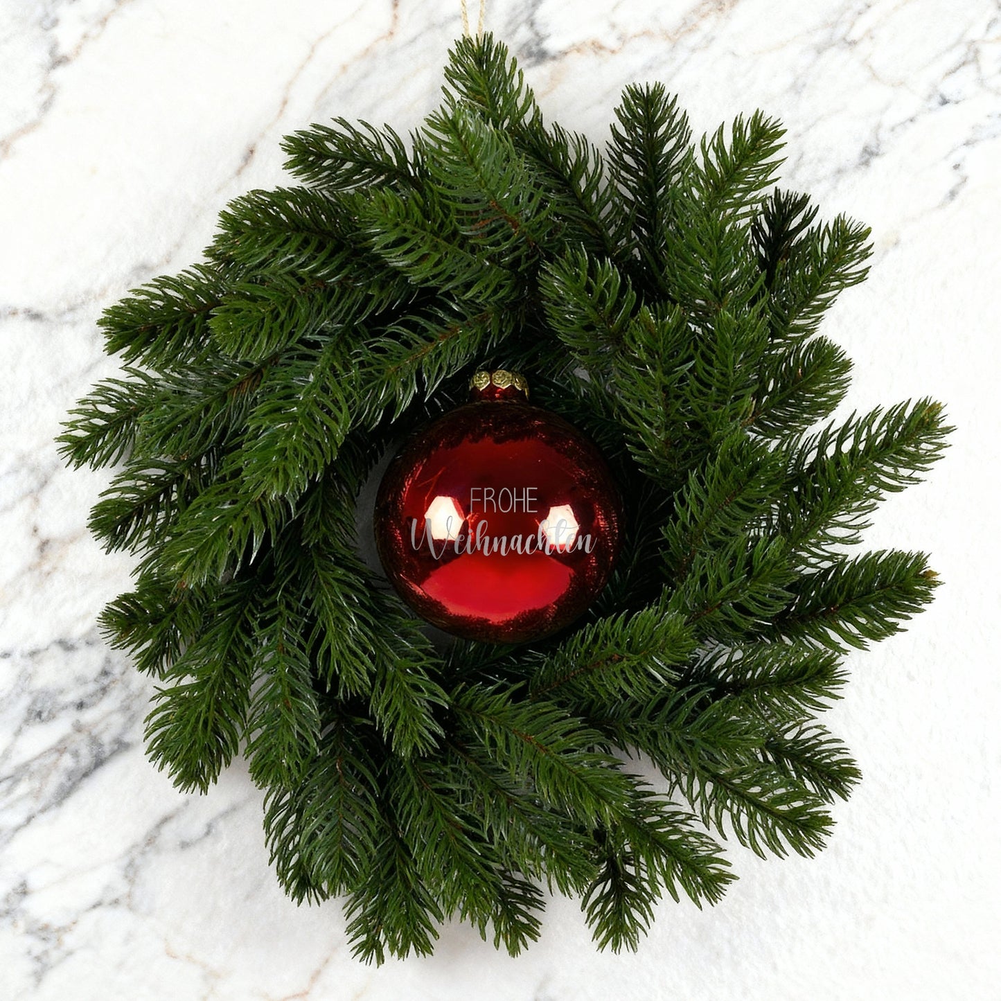 Weihnachtskranz mit roter Kugel Frohe Weihnachten auf weiß-marmoriertem Hintergrund
