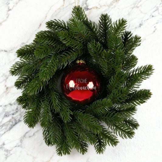 Weihnachtskranz mit roter Kugel Frohe Weihnachten auf weiß-marmoriertem Hintergrund