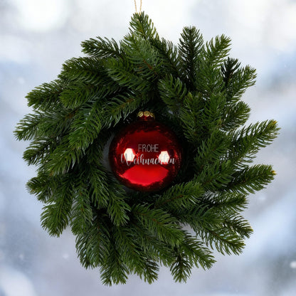 Türkranz mit roter Weihnachtskugel Frohe Weihnachten vor winterlicher Fensterszene