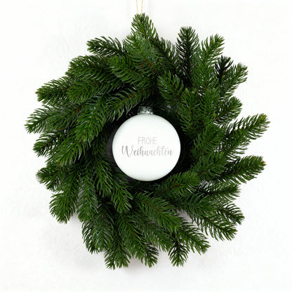 Weihnachtskranz mit weißer gravierter Kugel Frohe Weihnachten auf weißem Untergrund