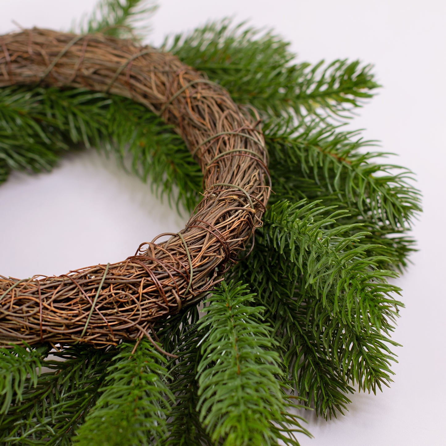 Nahaufnahme des Kranzrahmens aus Zweigen und künstlichen Tannenzweigen