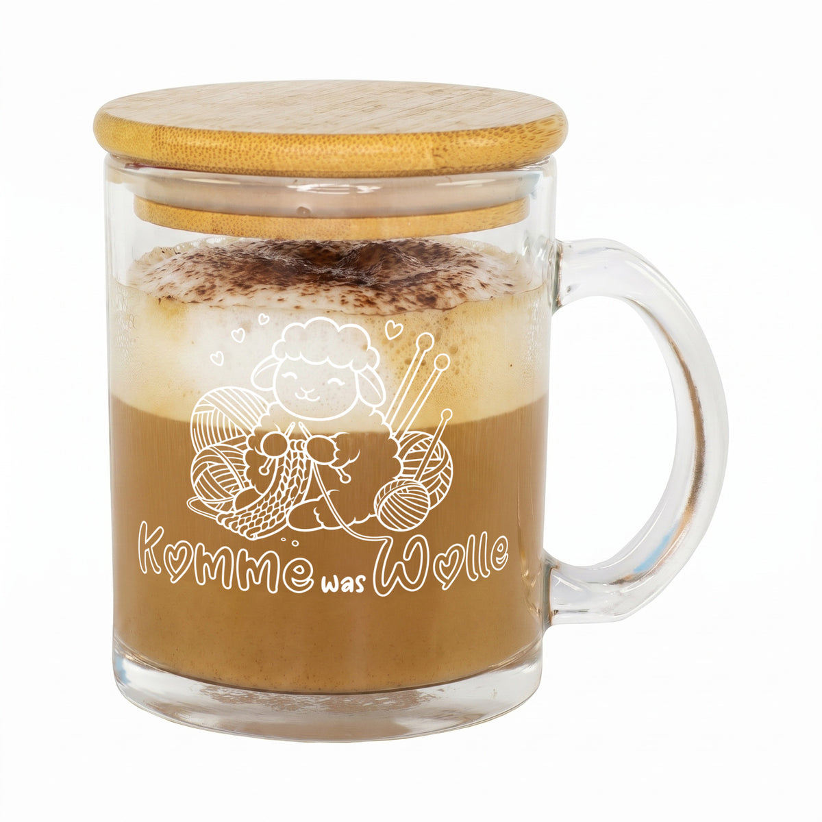 Freigestellte Glastasse mit Cappuccino, Bambusdeckel und weißem Schaf-Motiv „Komme was Wolle“