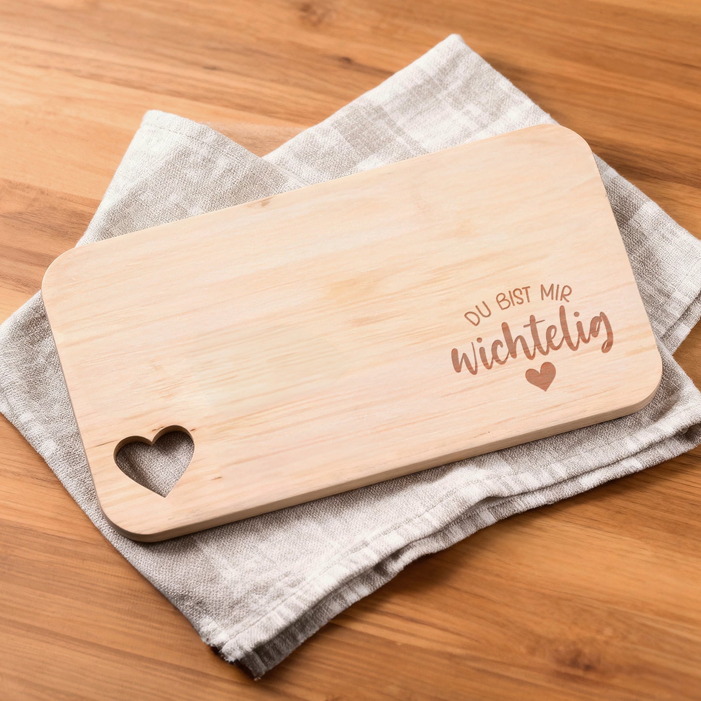 Erlenholz-Brettchen mit Gravur „Du bist mir wichtelig“ auf Stofftuch liegend.