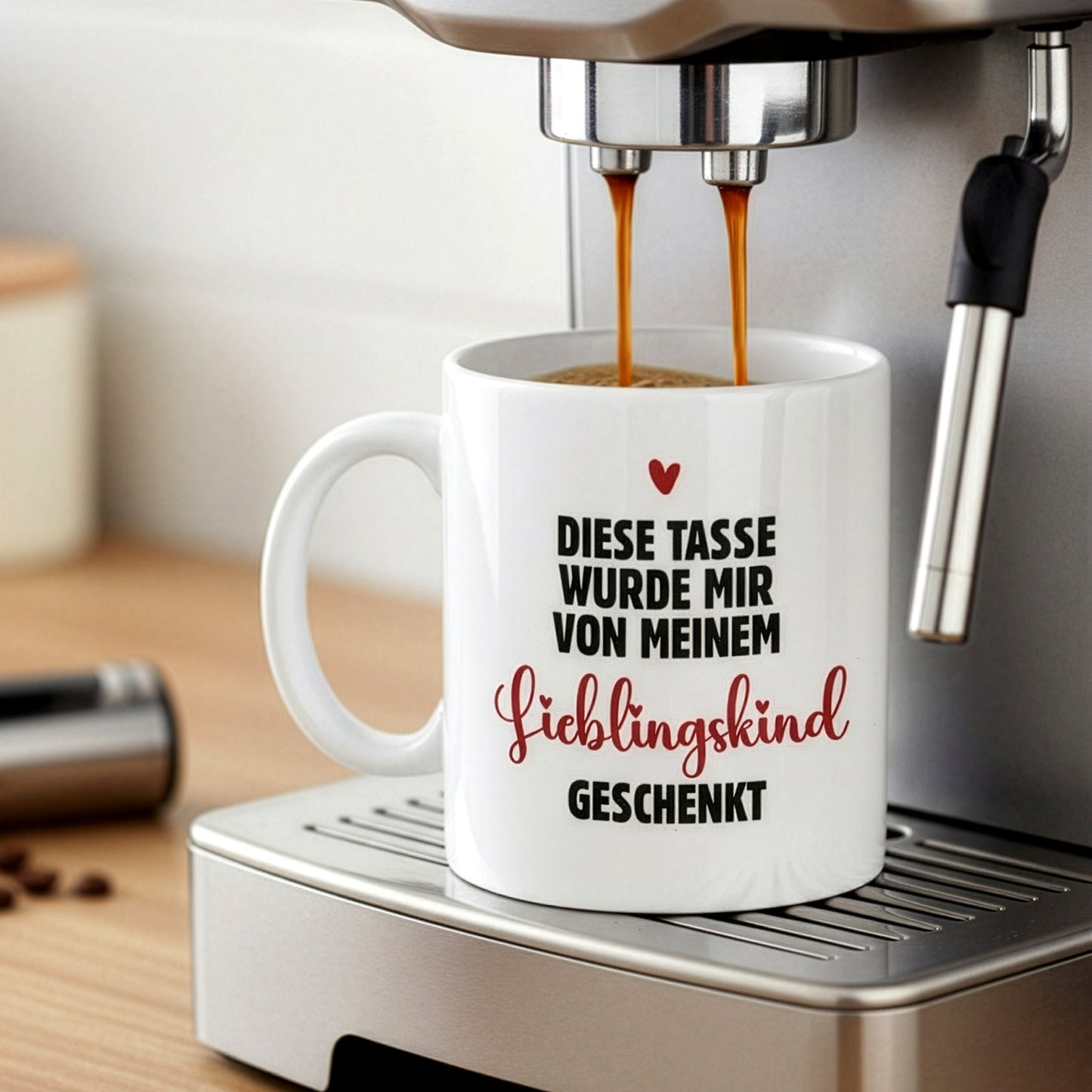 Kaffeetasse mit Herzmotiv und Schriftzug „Lieblingskind“, platziert unter einer Kaffeemaschine beim Befüllen