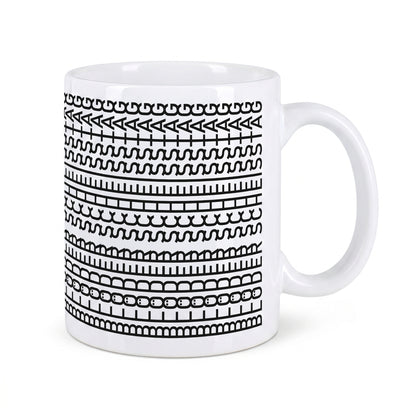 Freigestellte weiße Keramiktasse mit schwarzem grafischem Muster und verstecktem Spruch auf weißem Hintergrund