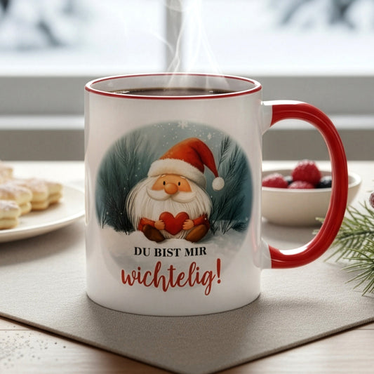 Dampfende Tasse mit Wichtel und Spruch „Du bist mir wichtelig!“ auf Tisch mit Gebäck und winterlicher Deko – Nahaufnahme.
