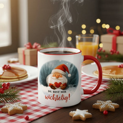 Tasse mit Wichtelmotiv und Spruch „Du bist mir wichtelig!“ auf gedecktem Frühstückstisch mit Gebäck, Tannenzweigen und Lichtern – weihnachtliche Atmosphäre.