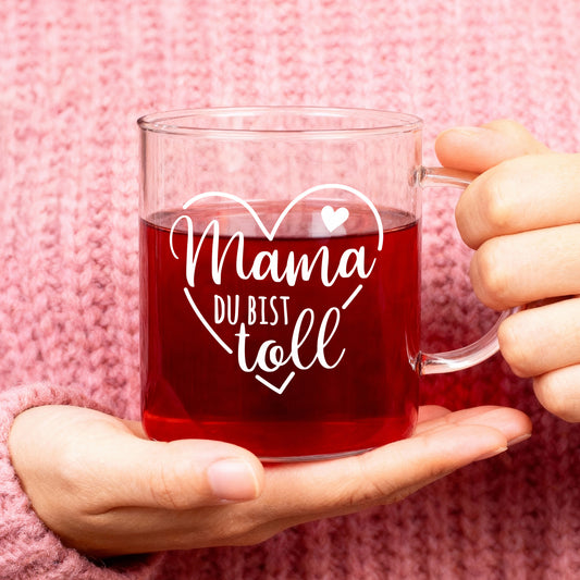 Teeglas mit Aufdruck Mama du bist toll und Herzmotiv auf gelbem Hintergrund mit Gebäck