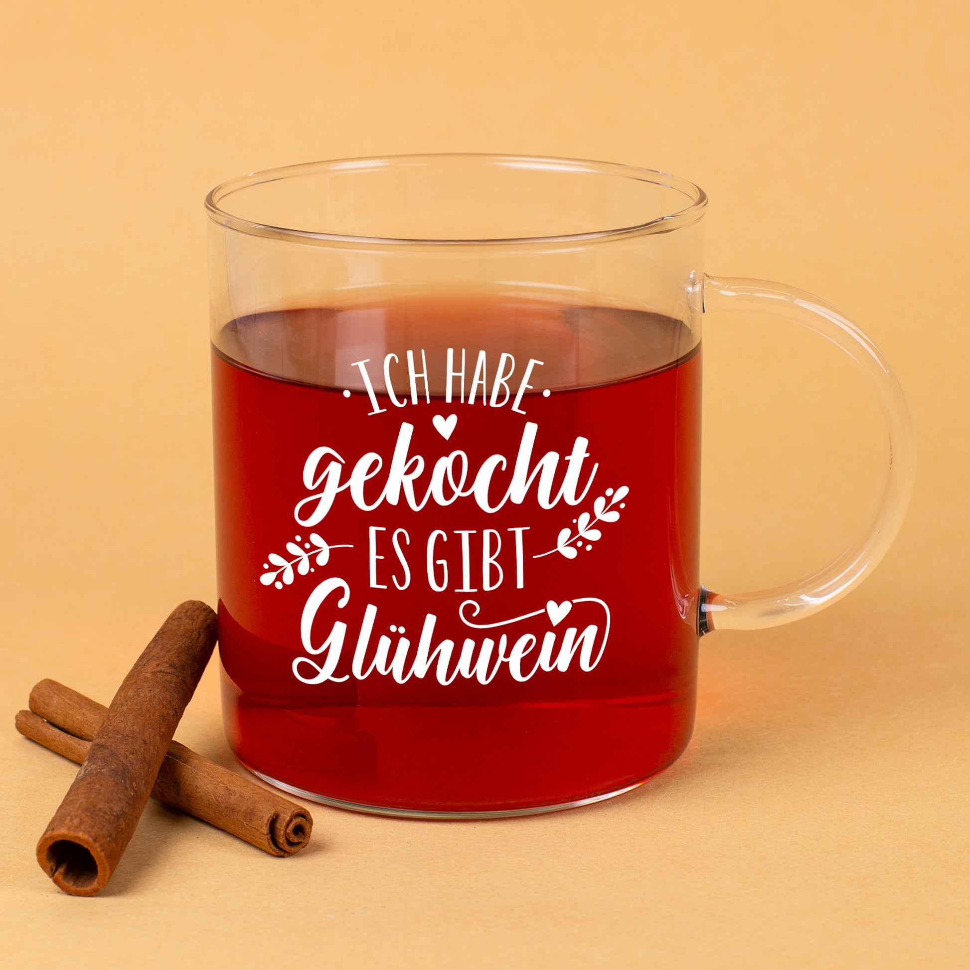 Glühwein-Teeglas von LEONARDO mit weißem Spruch „Ich habe gekocht – es gibt Glühwein“ und Zimtstangen als Deko.