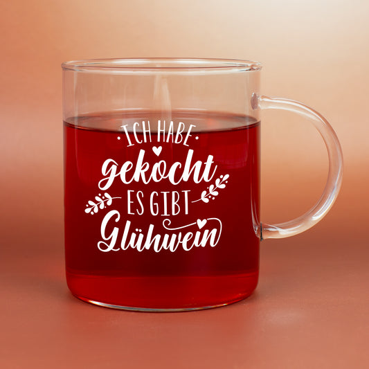 Teeglas von LEONARDO mit Winter-Spruch und rotem Heißgetränk vor warmem Hintergrund.