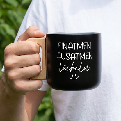 Schwarzer Edelstahlbecher mit Holzgriff und weißem Spruch Einatmen Ausatmen Lächeln