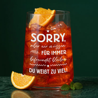 Trinkglas mit rotem Getränk, Eiswürfeln, Orangenscheibe und weißem Freundinnen-Spruch vor dunklem Hintergrund