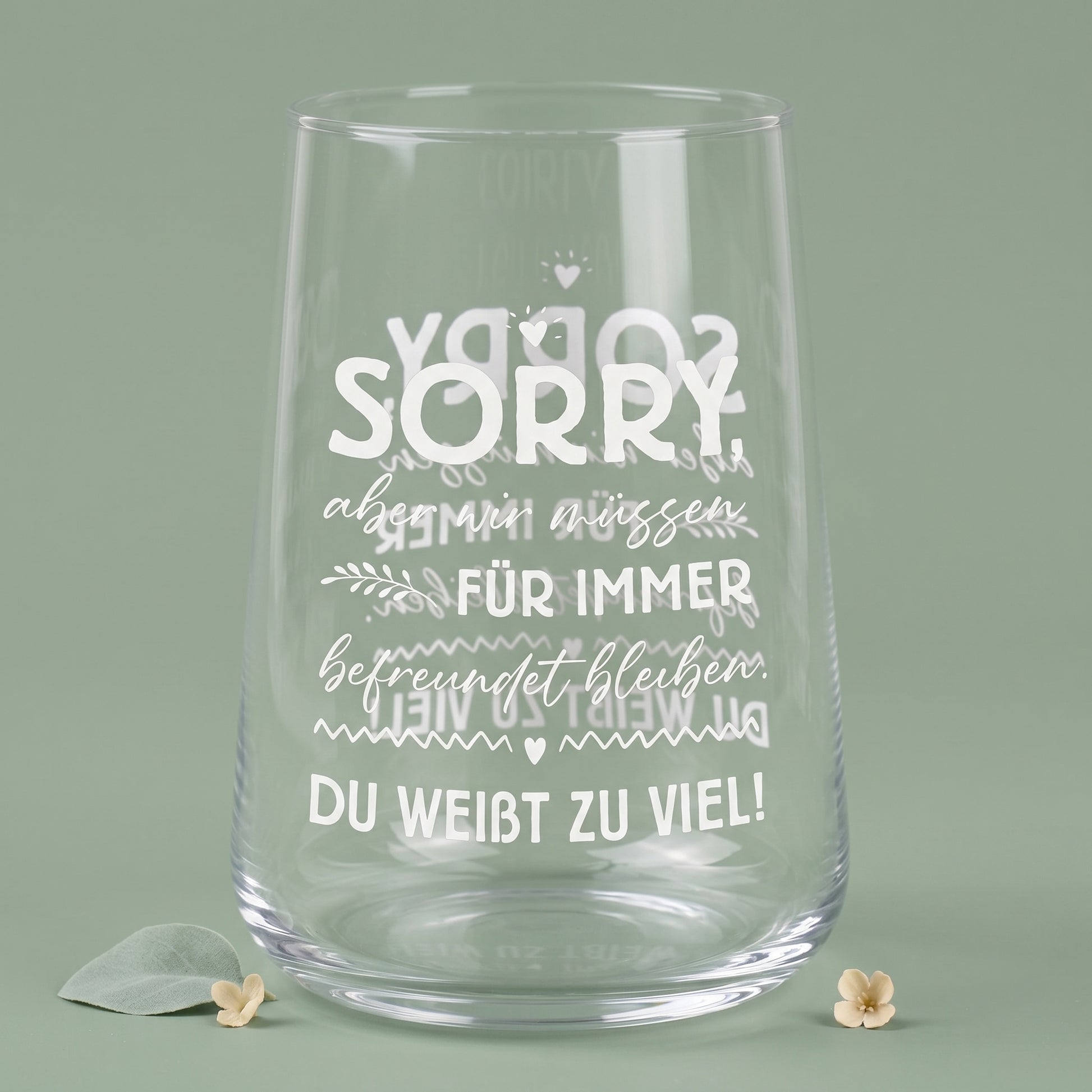 Leeres transparentes Trinkglas mit weißem Motivdruck und sichtbarer Spiegelung des Spruchs