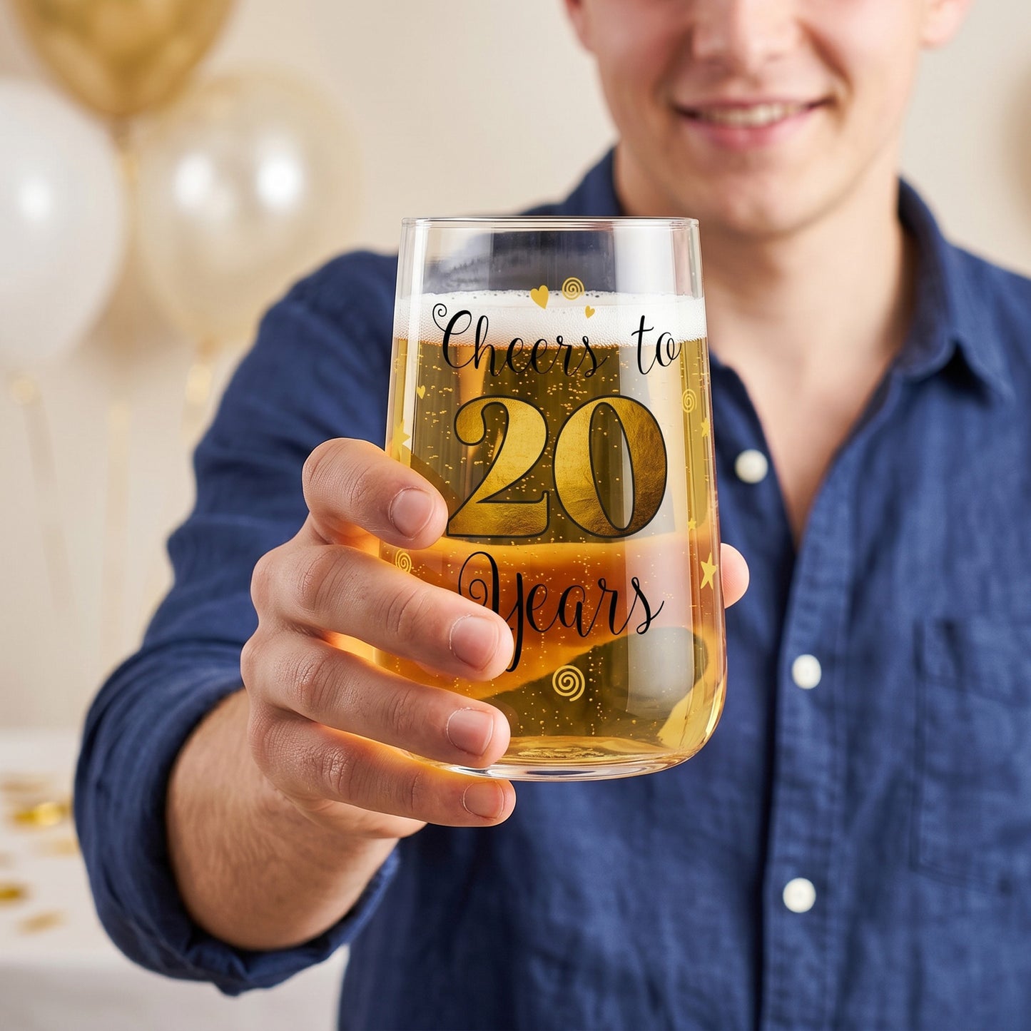 Bierglas oder Partyglas mit Cheers to 20 Years Aufdruck wird von einer Person zum Anstoßen gehalten
