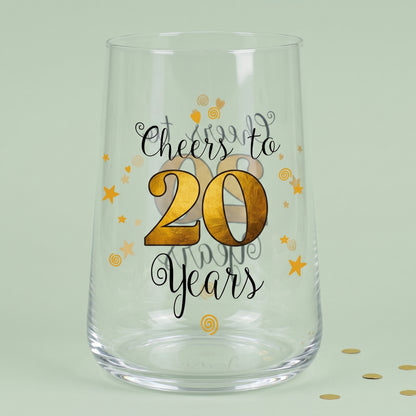 Leeres Trinkglas zum 20. Geburtstag mit Cheers to 20 Years Aufdruck und goldener 20 auf grünem Hintergrund