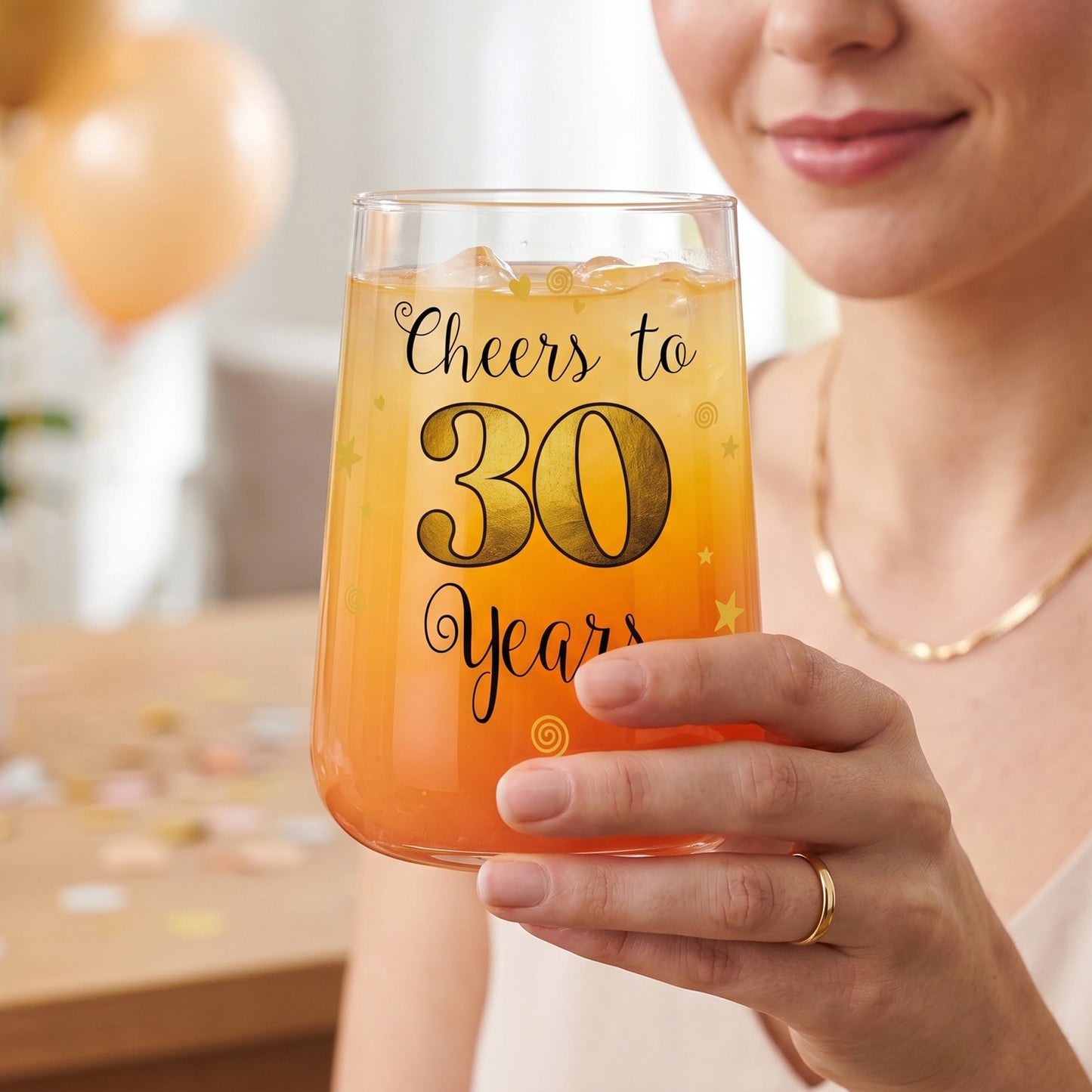 Trinkglas zum 30. Geburtstag mit Cheers to 30 Years Aufdruck wird von einer Frau gehalten